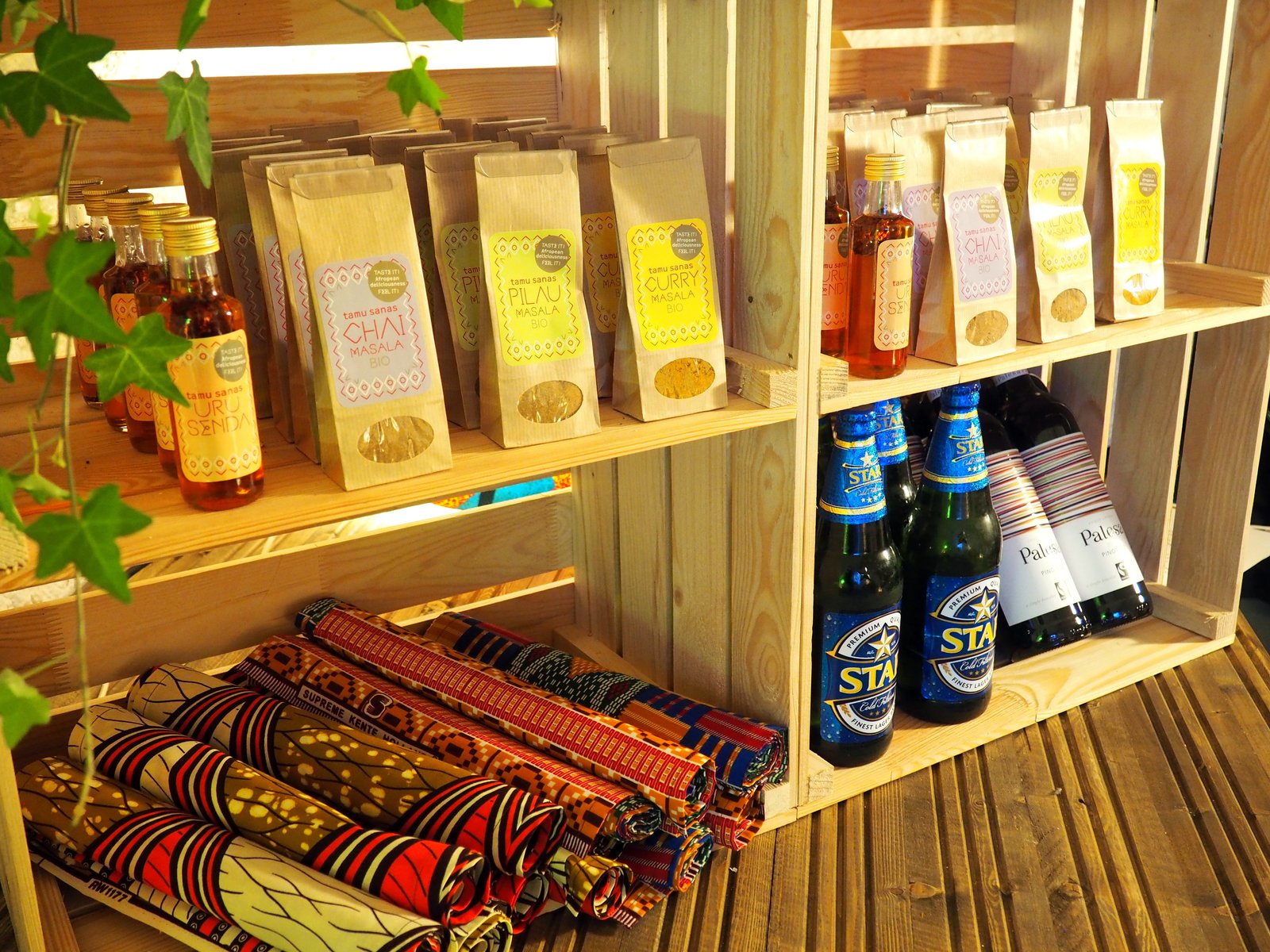 Shop-Regal mit tamu sana Gewürzen, Getränken und afrikanischen Stoffen